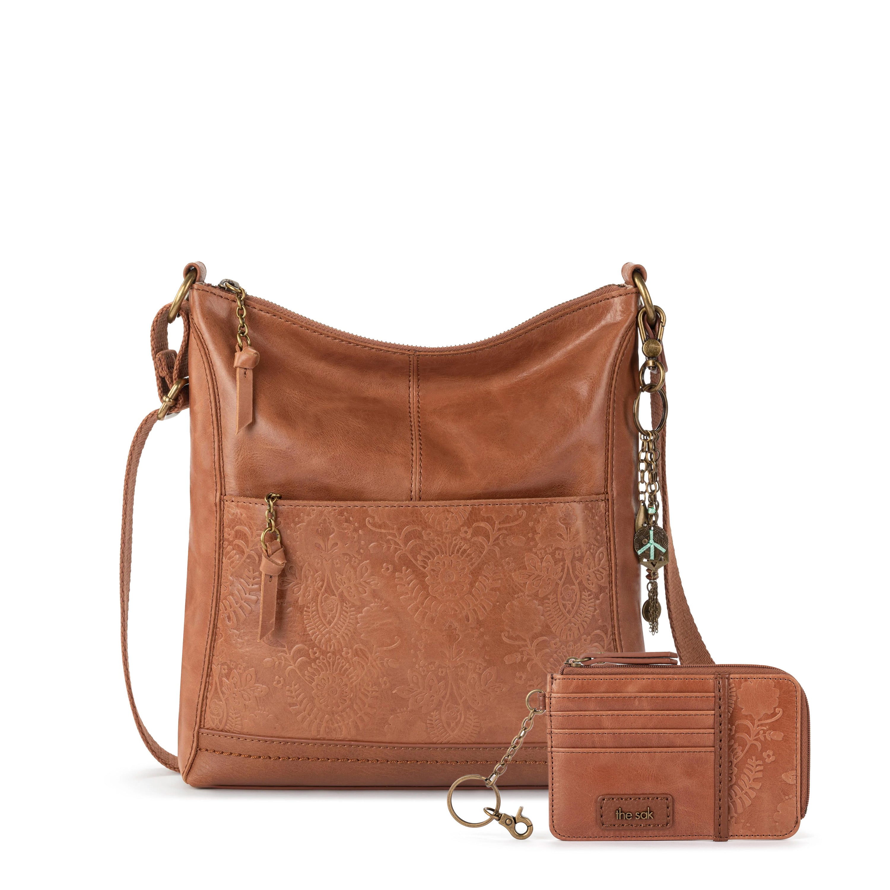 Tan leather crossbody bag with embossed floral pattern and matching card wallet with keychain attachment.