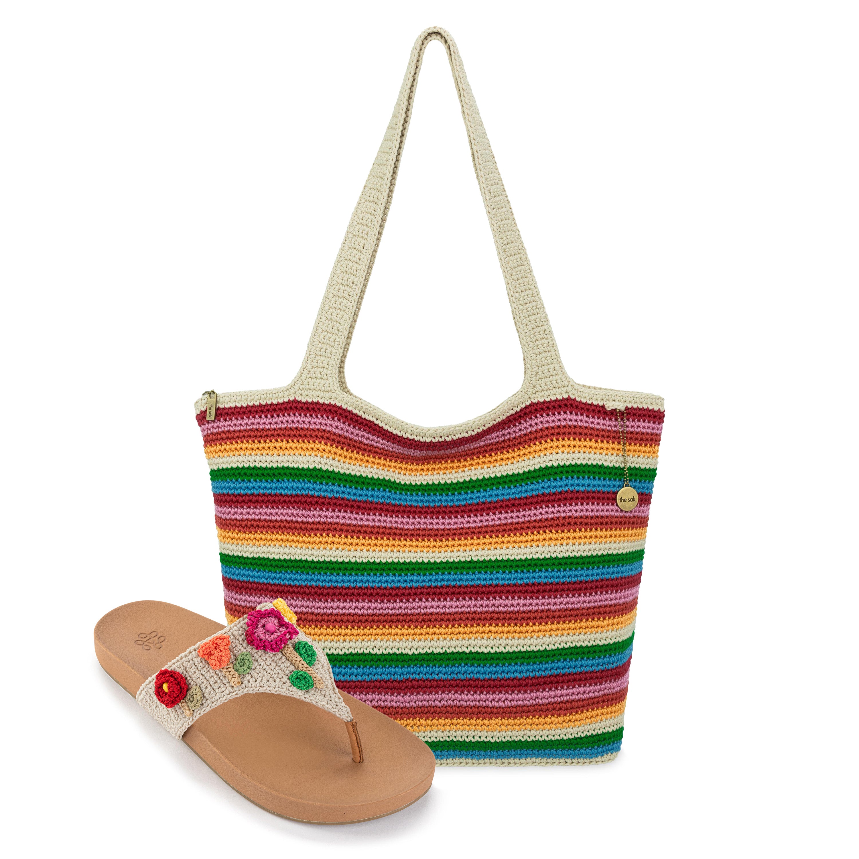 Cream tote bag with multicolor horizontal stripes and tan sandal with embroidered flowers on upper strap.